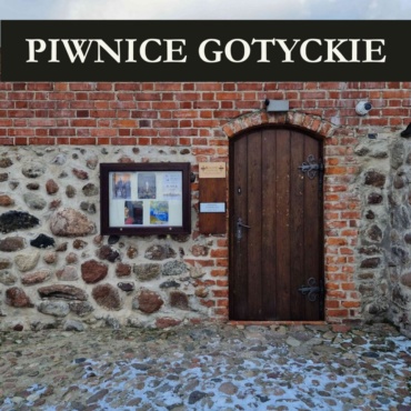 Drewniane drzwi w zamkowych murach - wejście do Piwnic Gotyckich. Podpis "Piwnice Gotyckie.