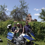 Cztery osoby stojące przy policyjnym motocyklu. W tle wieża Zamku w Liwie.