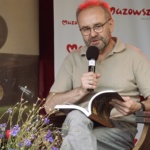 Siedzący mężczyzna mówiący do mikrofonu.