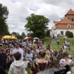 Tłum ludzi. W tle Zamek w Liwie.