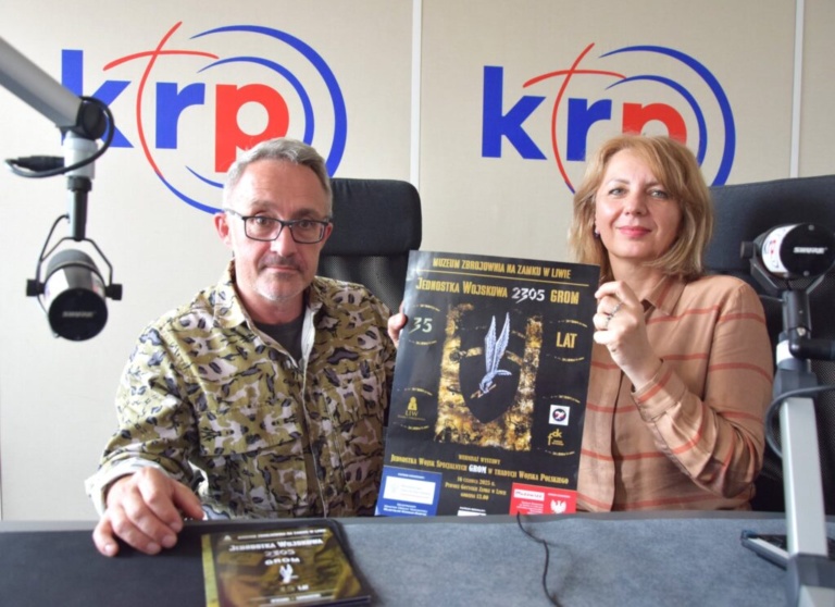 Dwie osoby - kobieta i mężczyzna - siedzący przy stoliku studia radiowego.