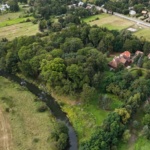 Zdjęcie z drona Dworu w Paplinie. Budynek otoczony zielenią - ogrodem i drzewami oraz rzeka Liwiec.