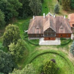 Zdjęcie z drona Dworu w Paplinie. Budynek otoczony zielenią - ogrodem i drzewami.