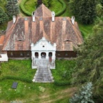 Zdjęcie z drona Dworu w Paplinie. Budynek otoczony zielenią - ogrodem i drzewami.