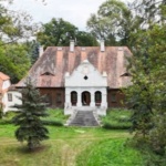 Zdjęcie z drona Dworu w Paplinie. Budynek otoczony zielenią - ogrodem i drzewami.