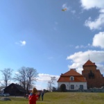 Dziecko puszczające latawiec. W tle Zamek w Liwie.